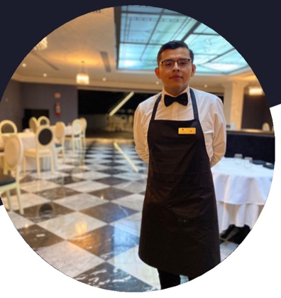 Axel Solis con uniforme de mesero en un restaurante
